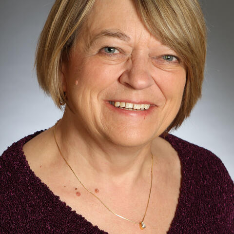 a woman smiling wearing a purple blouse